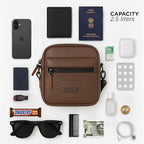 Brown Noma bag with essentials like phone, wallet, passport, and sunglasses, showcasing stylish and compact design.