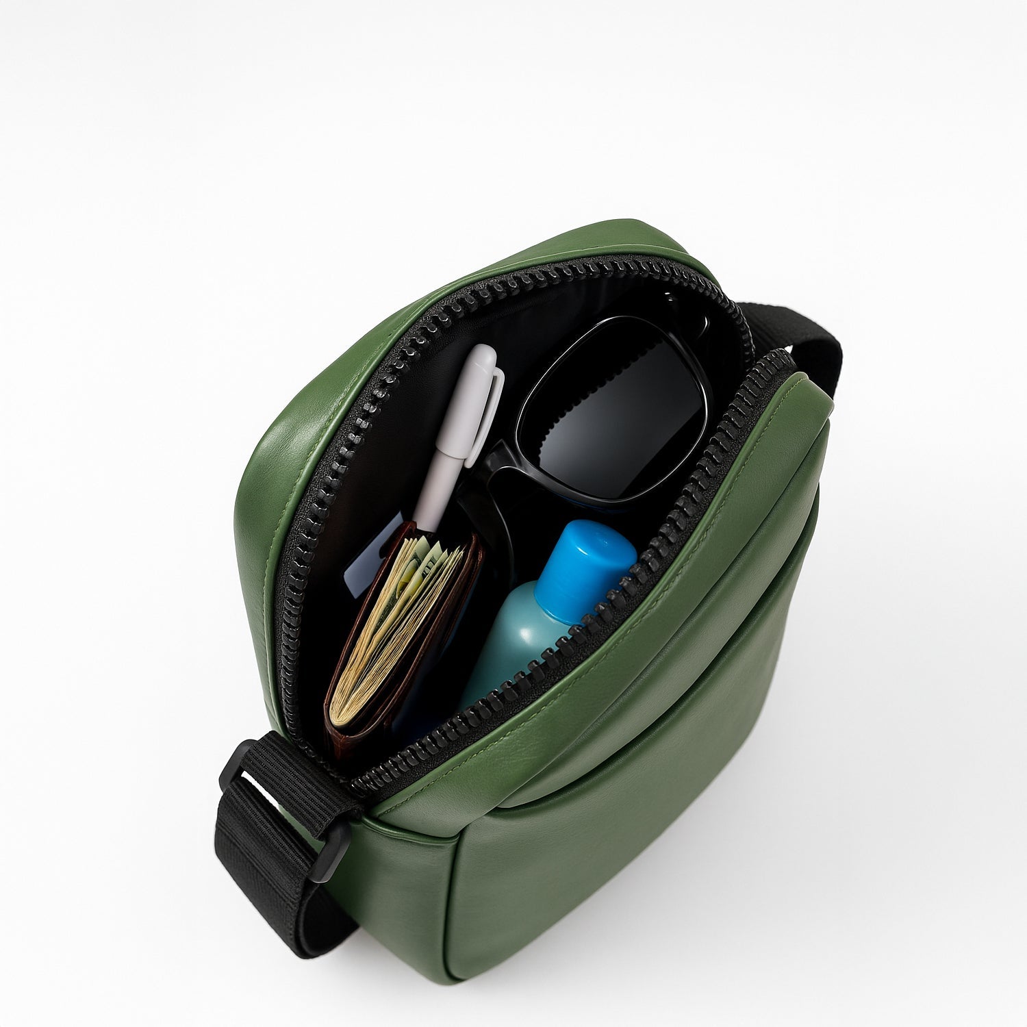 Top view of a stylish green sling bag showcasing organized essentials like a wallet, sunglasses, and a small bottle.