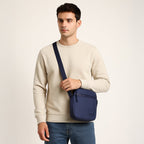 Man wearing a stylish navy sling bag, showcasing its compact design and adjustable shoulder strap.