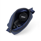 Open navy bag showing Nikon camera accessories including lens cap and buttons.