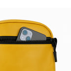 Close-up of a mustard bag zipper pocket with a smartphone partially visible, showcasing efficient organization.