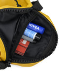 Interior view of THE BLOC mustard bag with essentials like lotion, pens, and a credit card organized inside.