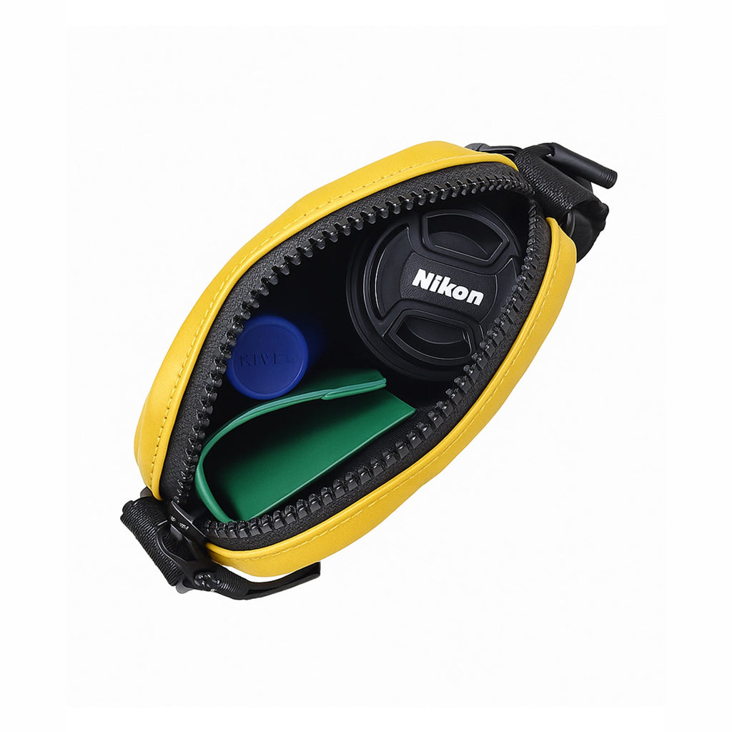 Interior view of THE BLOC mustard bag showing Nikon lens cap and accessories organized inside.