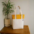 Modern offwhite and yellow tote bag on a wooden table, perfect for everyday use and stylish organization.