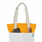 The Skylin off-white and yellow canvas tote bag featuring organized storage with essentials like a wallet and comb.