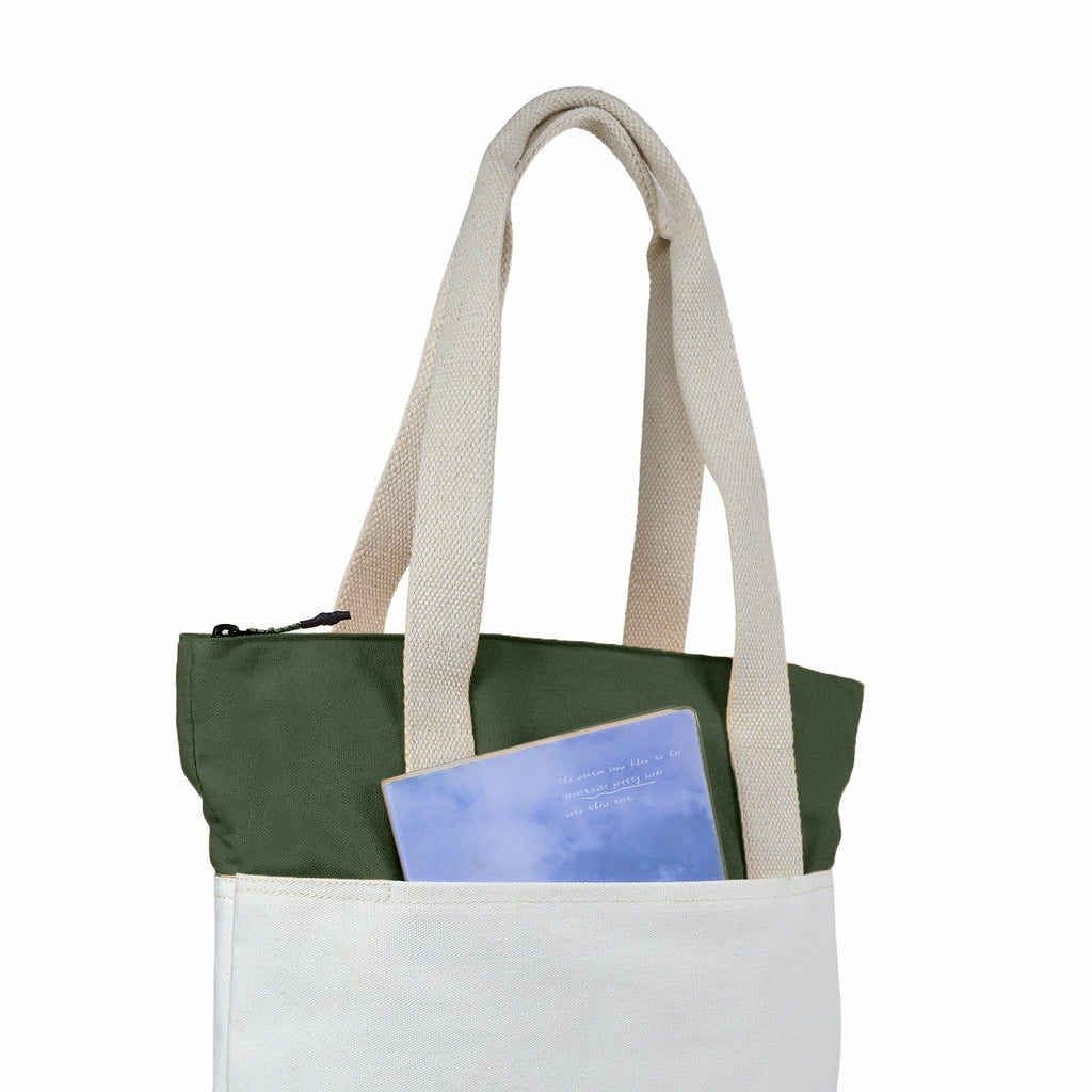 The Skylin tote bag in off-white and army green with a notebook in the front pocket.