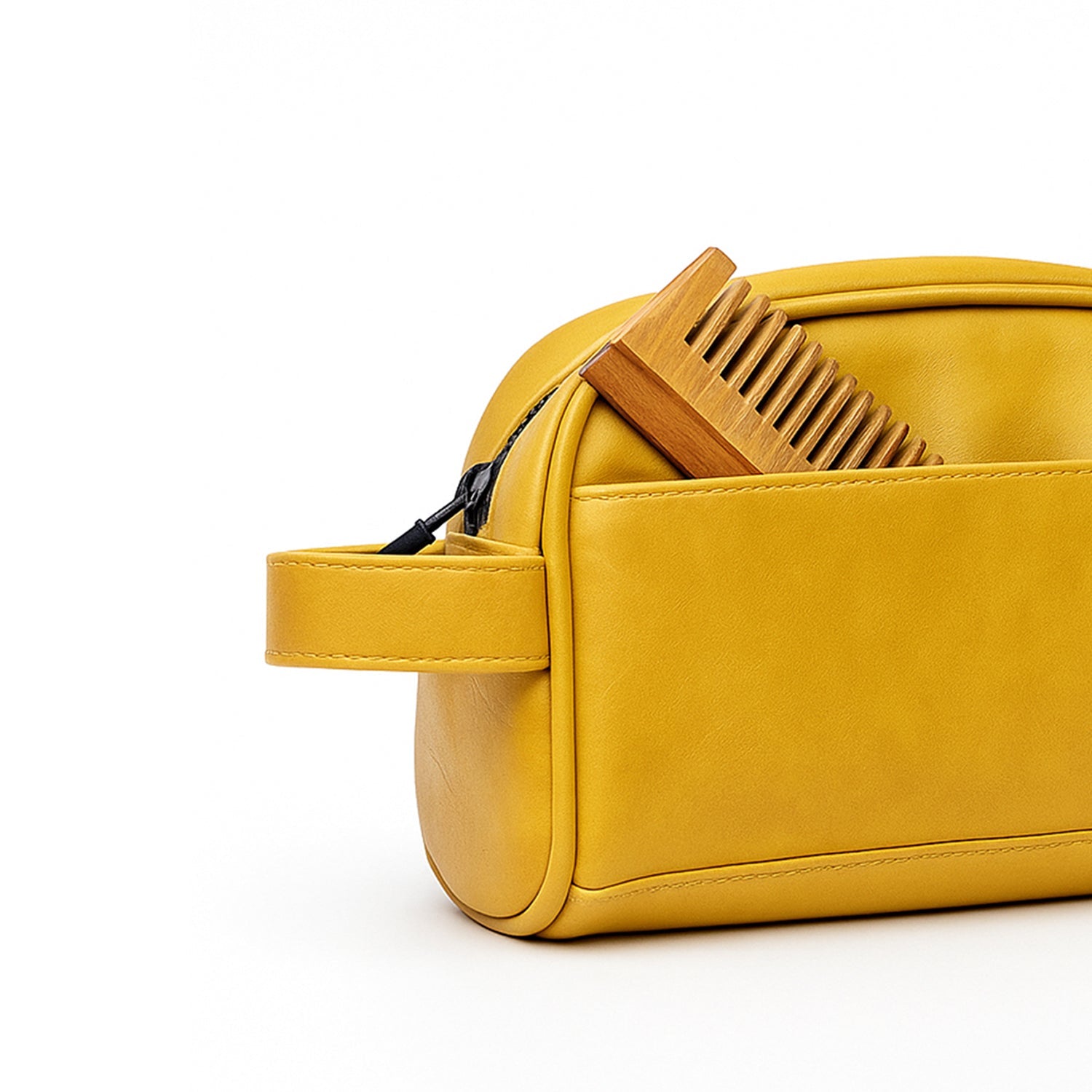 Chic mustard yellow toiletry bag made of vegan leather, featuring a wooden comb peeking from the front pocket.