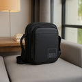 Stylish black crossbody bag with adjustable strap, featuring a sleek design and organized compartments for essentials.