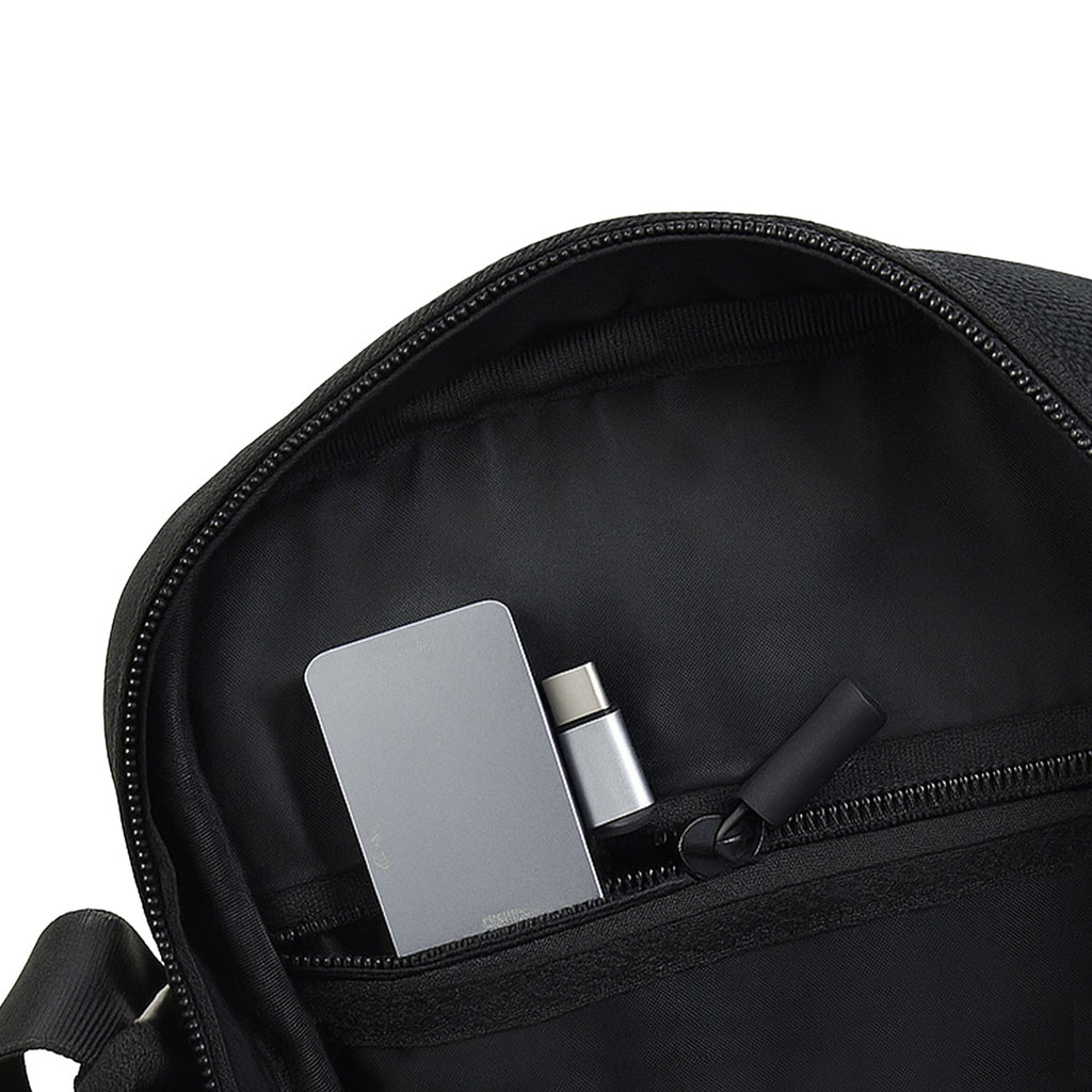 Interior view of Luno Black bag showing compact organization with zipper pocket and essentials like phone and wallet.