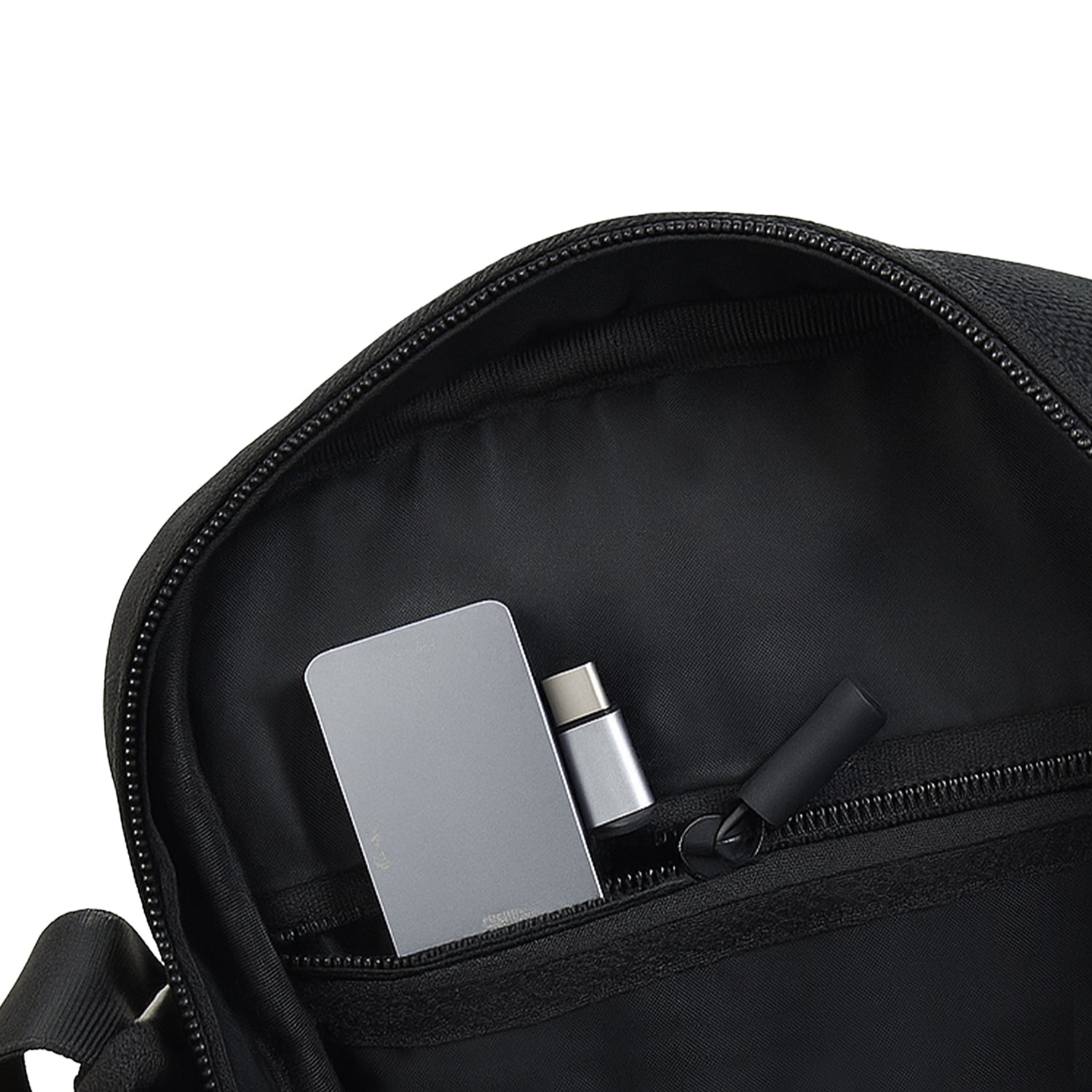 Interior view of Luno Black bag showing compact organization with zipper pocket and essentials like phone and wallet.