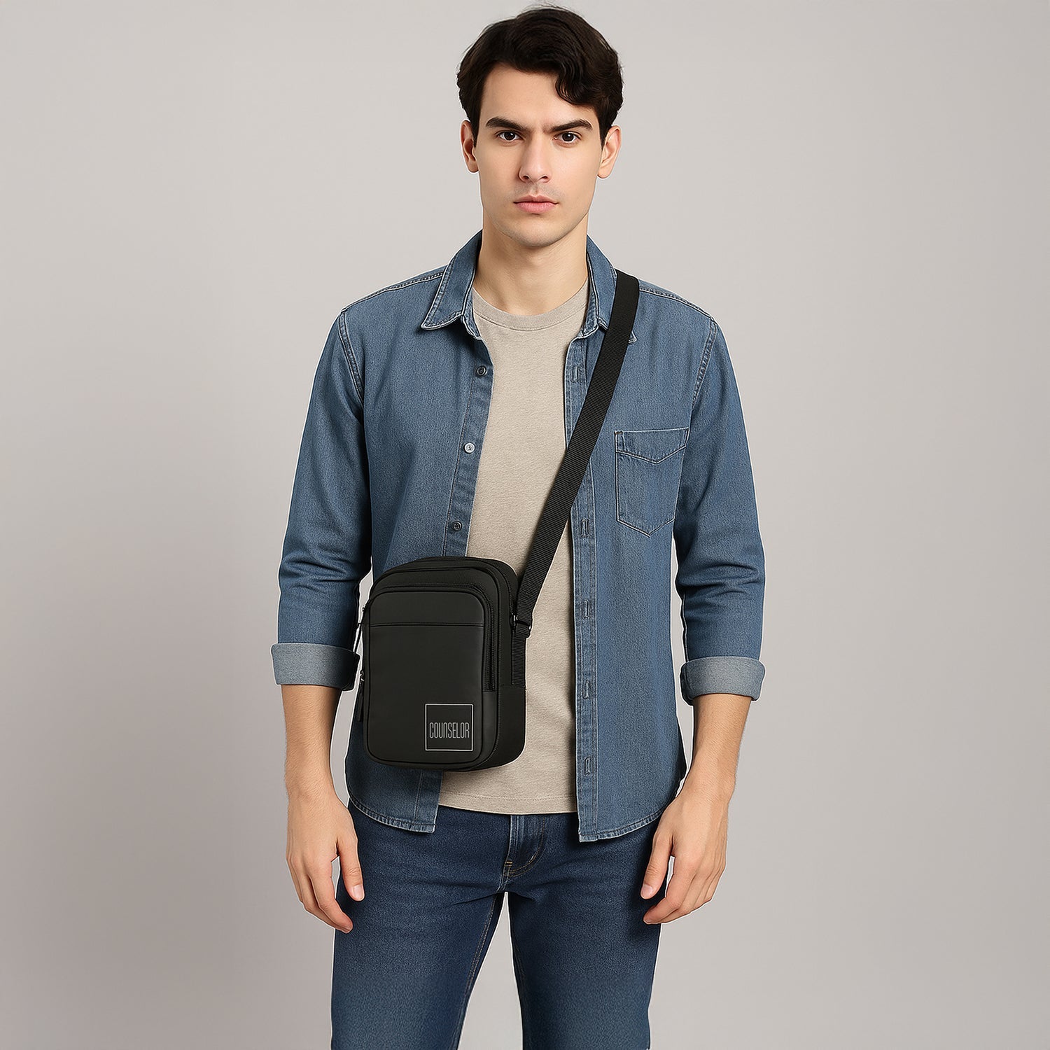Stylish young man wearing THE LUNO - BLACK crossbody bag, showcasing its sleek design and functionality.