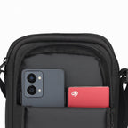 Close-up of the Luno Black Sling bag displaying phone and card in the front pocket, showcasing its smart organization design.