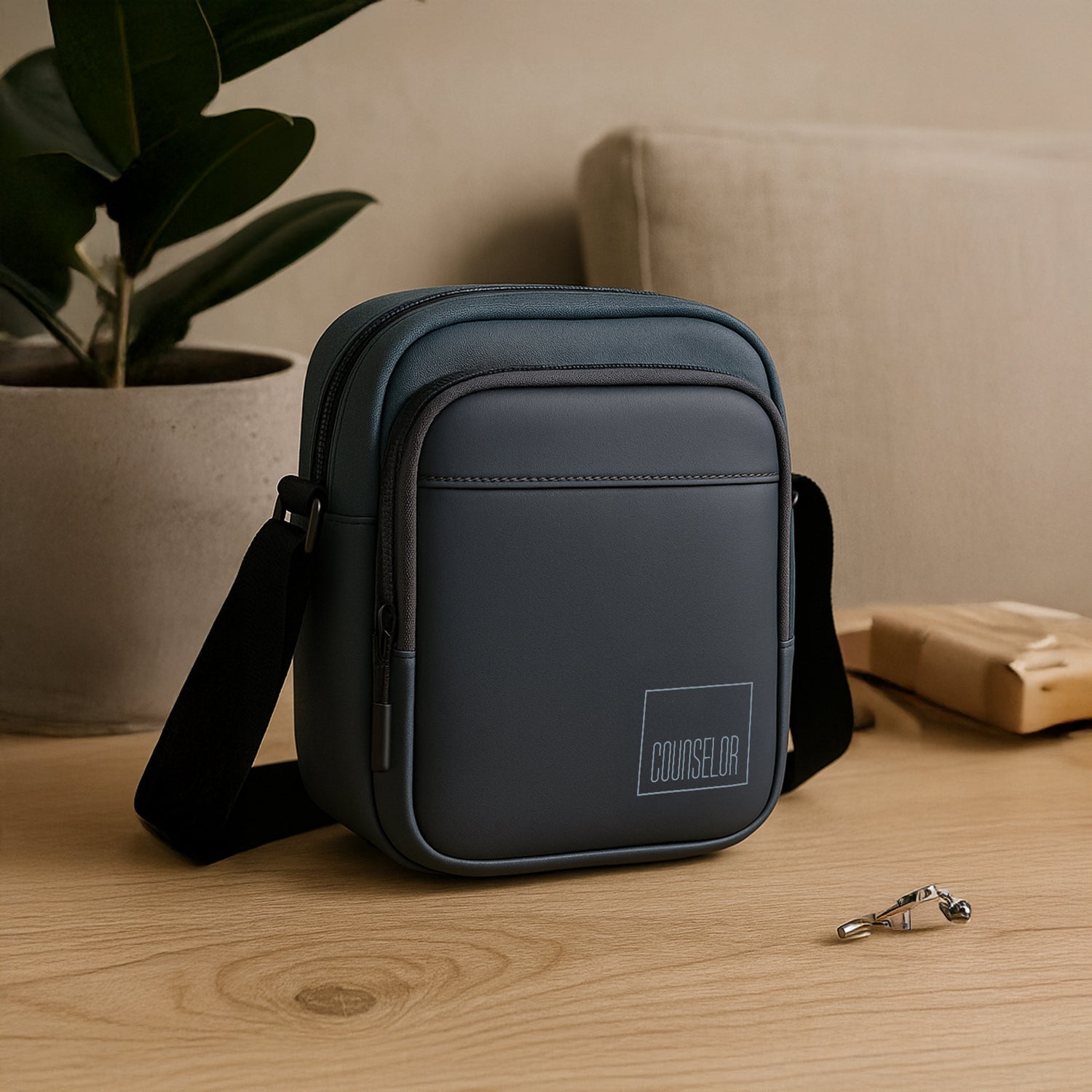 Stylish grey crossbody bag on a wooden table, featuring adjustable strap and zippered compartments.