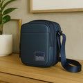 Navy blue Luno Sling bag on a wooden surface, showcasing stylish design and adjustable strap.