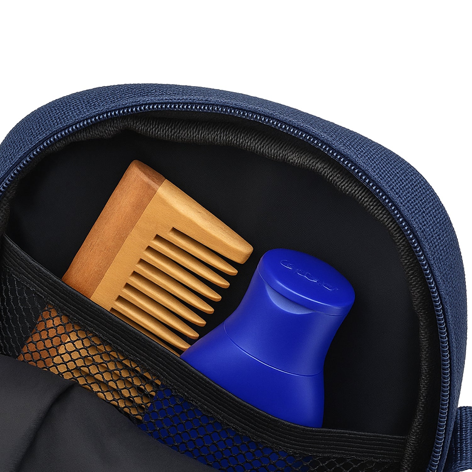 Interior view of Luno Navy sling bag showing a wooden comb and blue bottle in the mesh pocket.