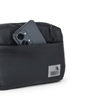 The Avelin black waistpack with smartphone in front pocket, showcasing minimalist design for everyday use.