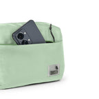 The Avelin waistpack in pista green, showcasing smart storage with a phone in the front pocket.