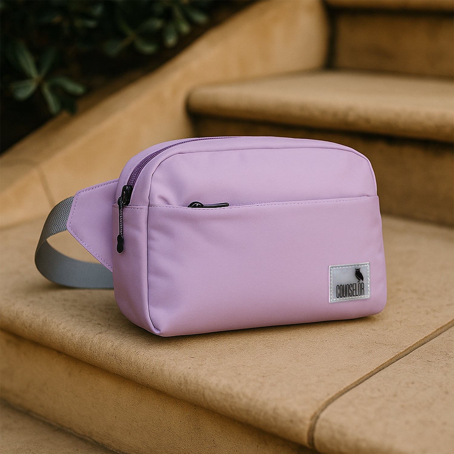The Avelin pink waistpack resting on steps, showcasing its minimalist design and compact build.