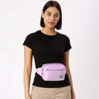 Woman wearing The Avelin pink waistpack, showcasing its minimalist design and adjustable strap for versatile styling.