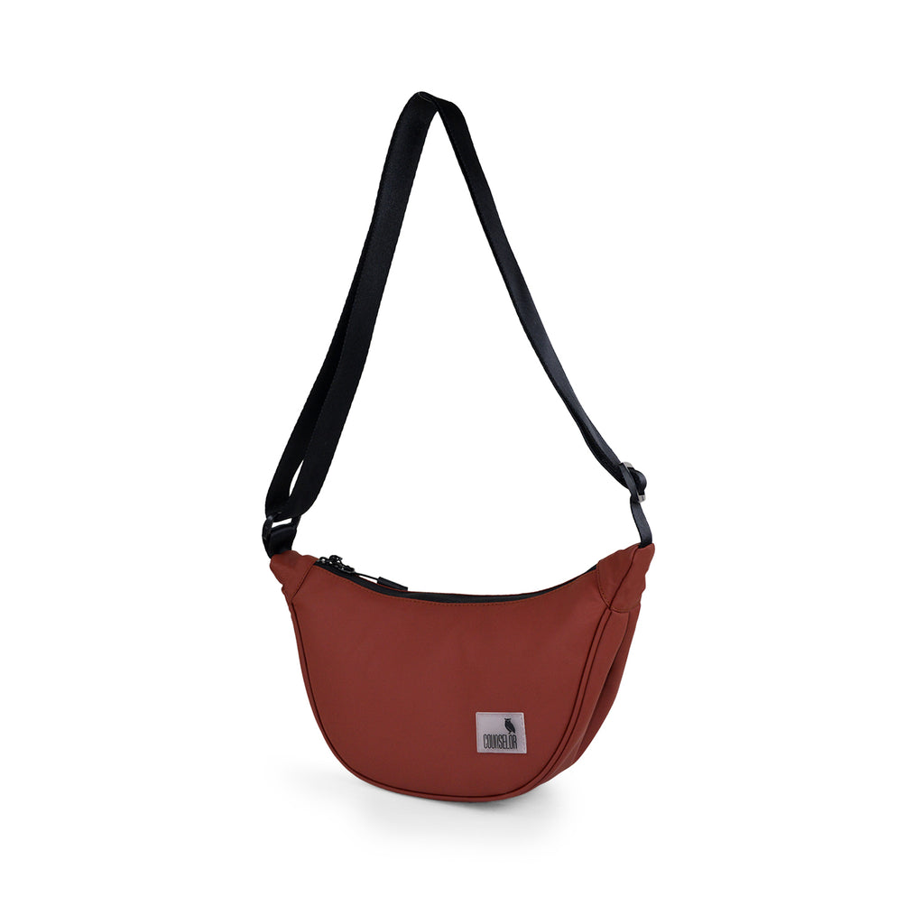 The Zuki side sling bag in rust color, featuring an adjustable strap and sleek design for daily use.