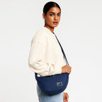 Woman wearing THE ZUKI navy sling bag, showcasing its sleek design and adjustable strap for versatile wear.