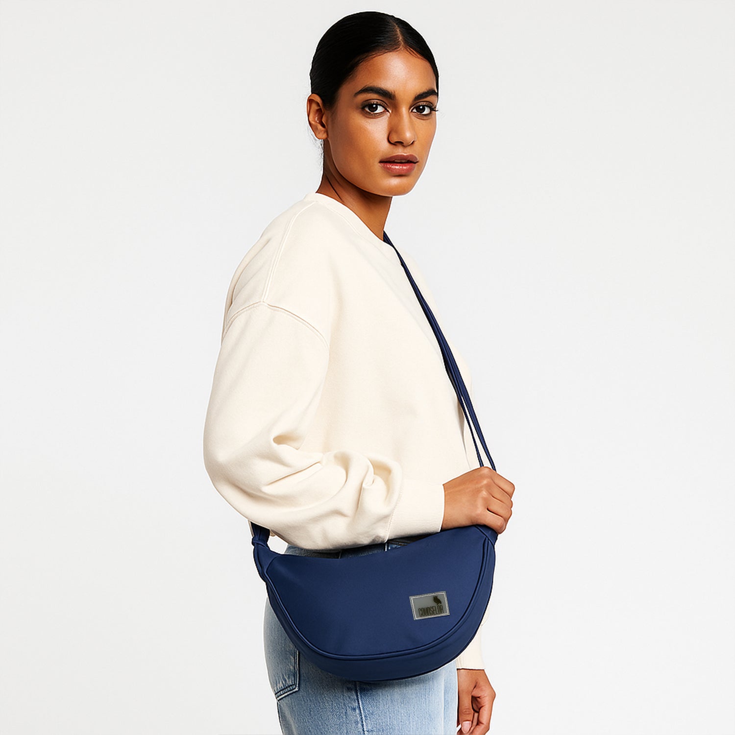 Woman wearing THE ZUKI navy sling bag, showcasing its sleek design and adjustable strap for versatile wear.