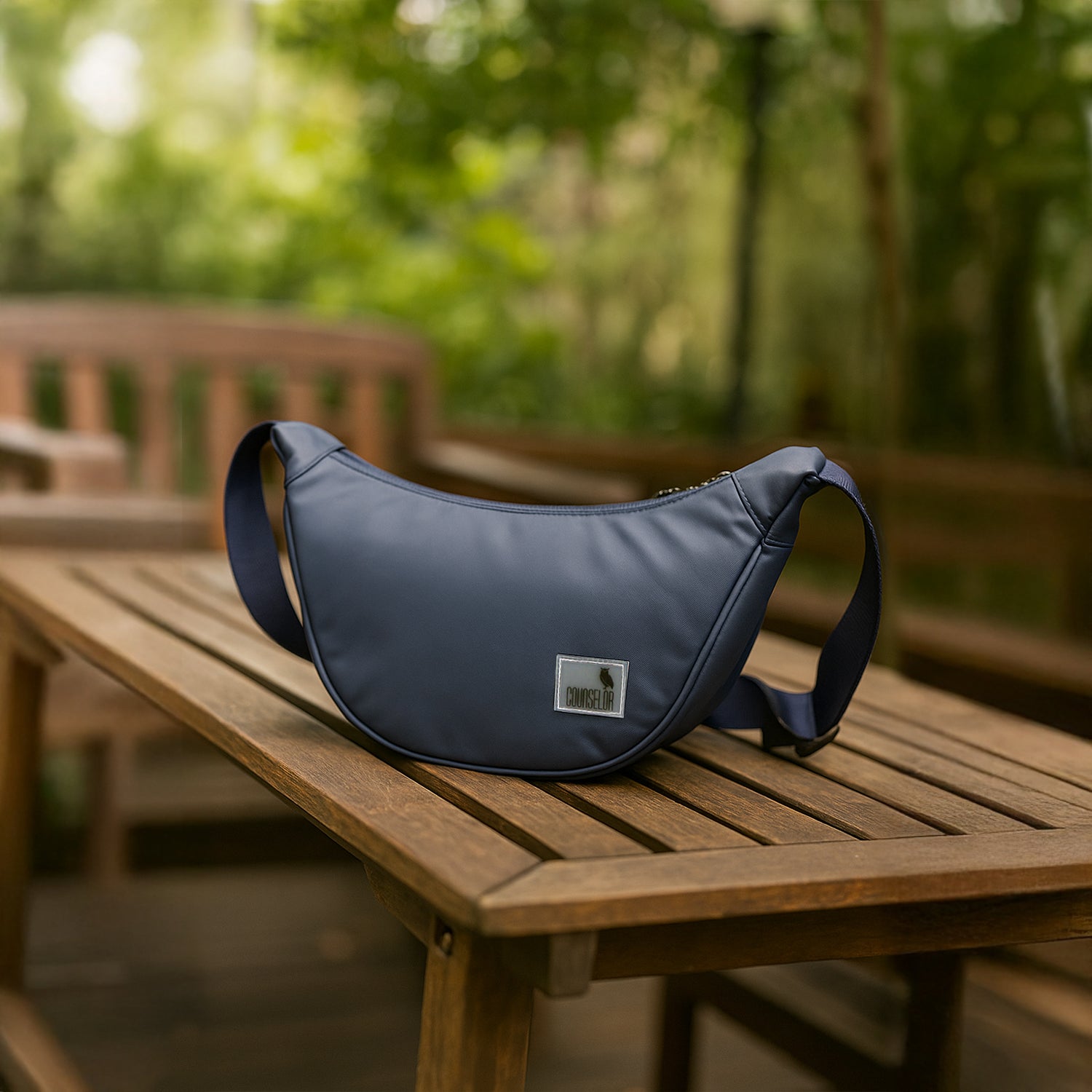 The Zuki navy sling bag on a wooden table, showcasing its sleek design and functional style for everyday use.