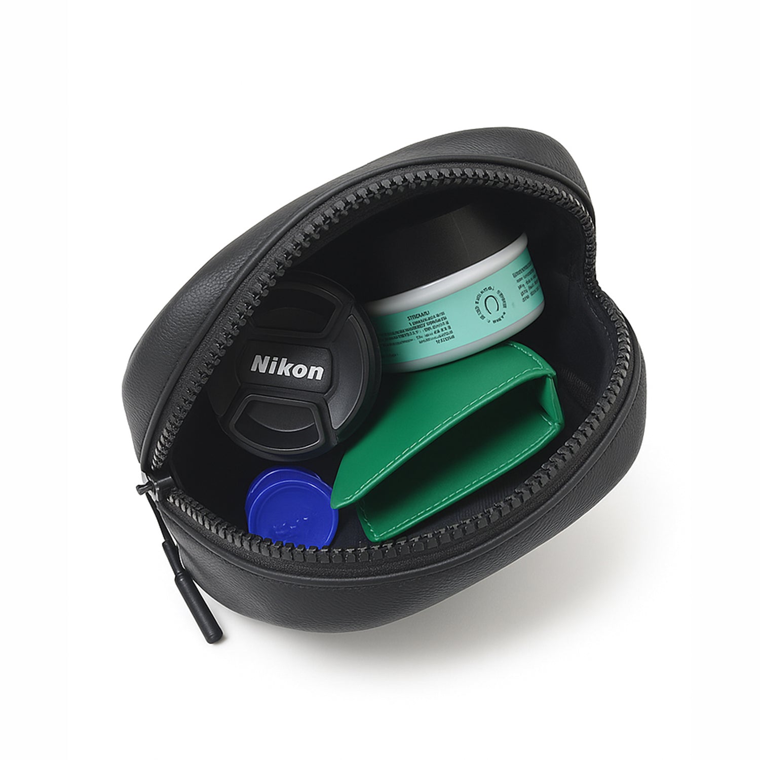 Open black camera bag showing Nikon lens cap, skincare products, and a green wallet.