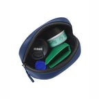 Inside view of a navy zippered pouch containing Nikon lens cap, skincare, and green wallet.