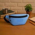 Sky blue waist pouch labeled 'COUNSELOR' on a wooden desk with a plant and notebook.