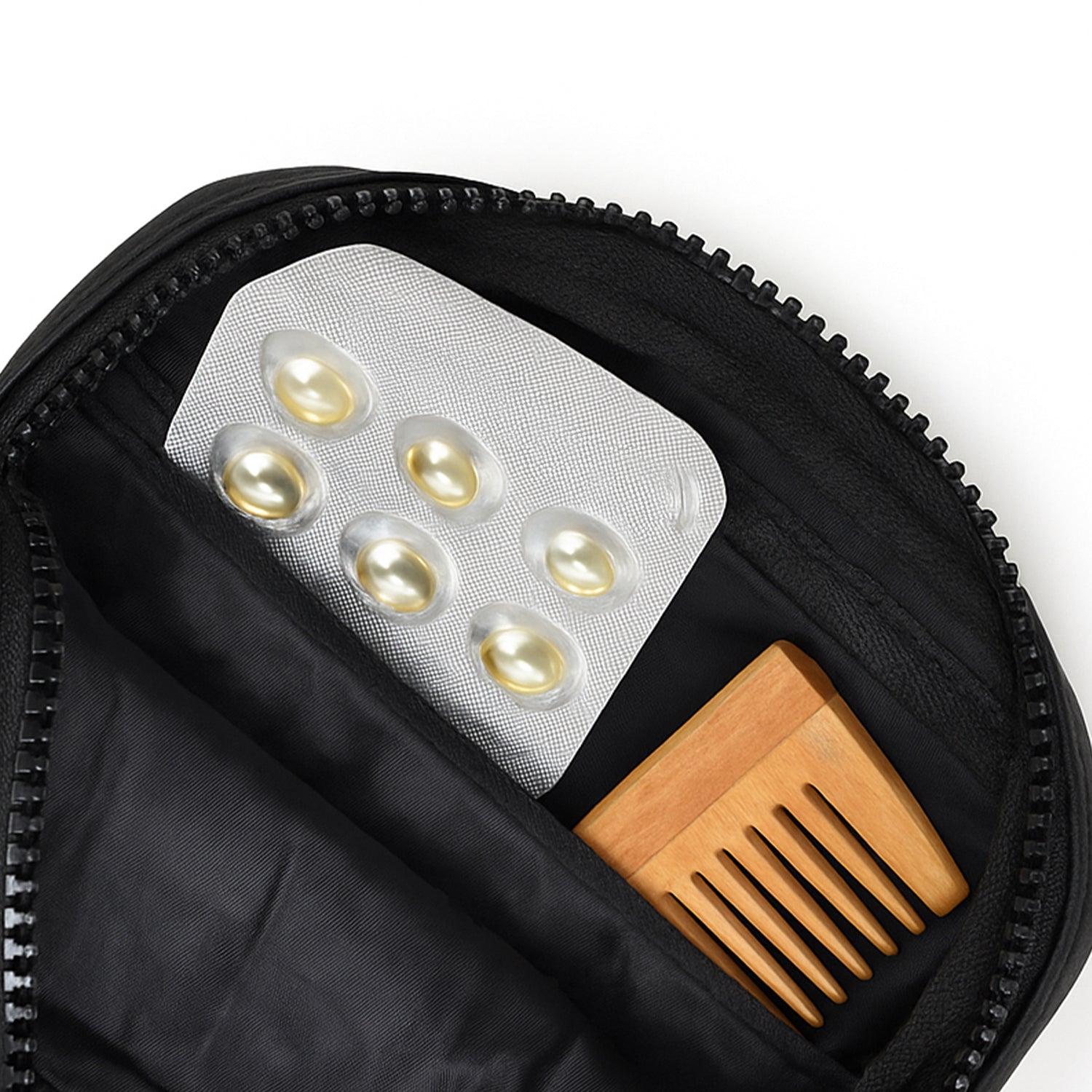 Inside view of a black bag showing a pack of capsules and a wooden comb.