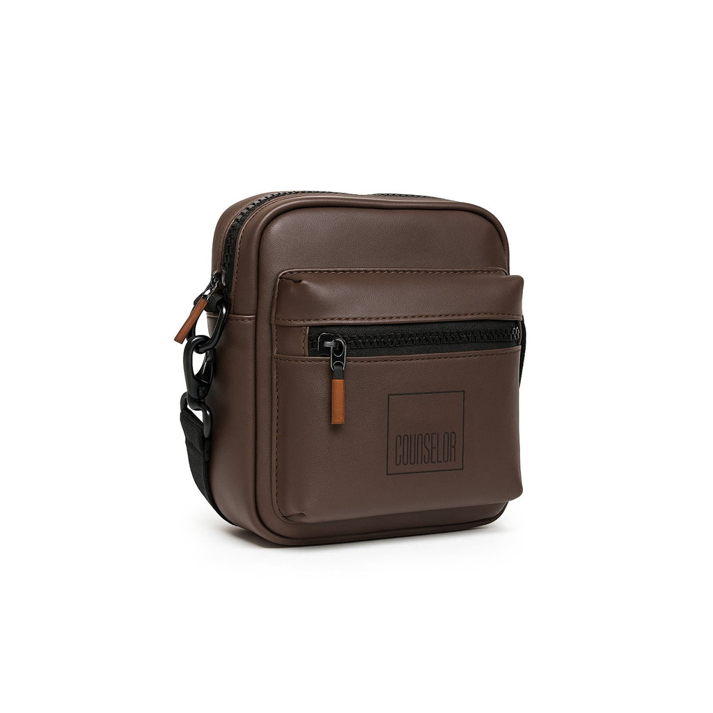 Stylish brown Noma bag made of vegan leather, featuring adjustable strap and front zipper pocket for convenience.