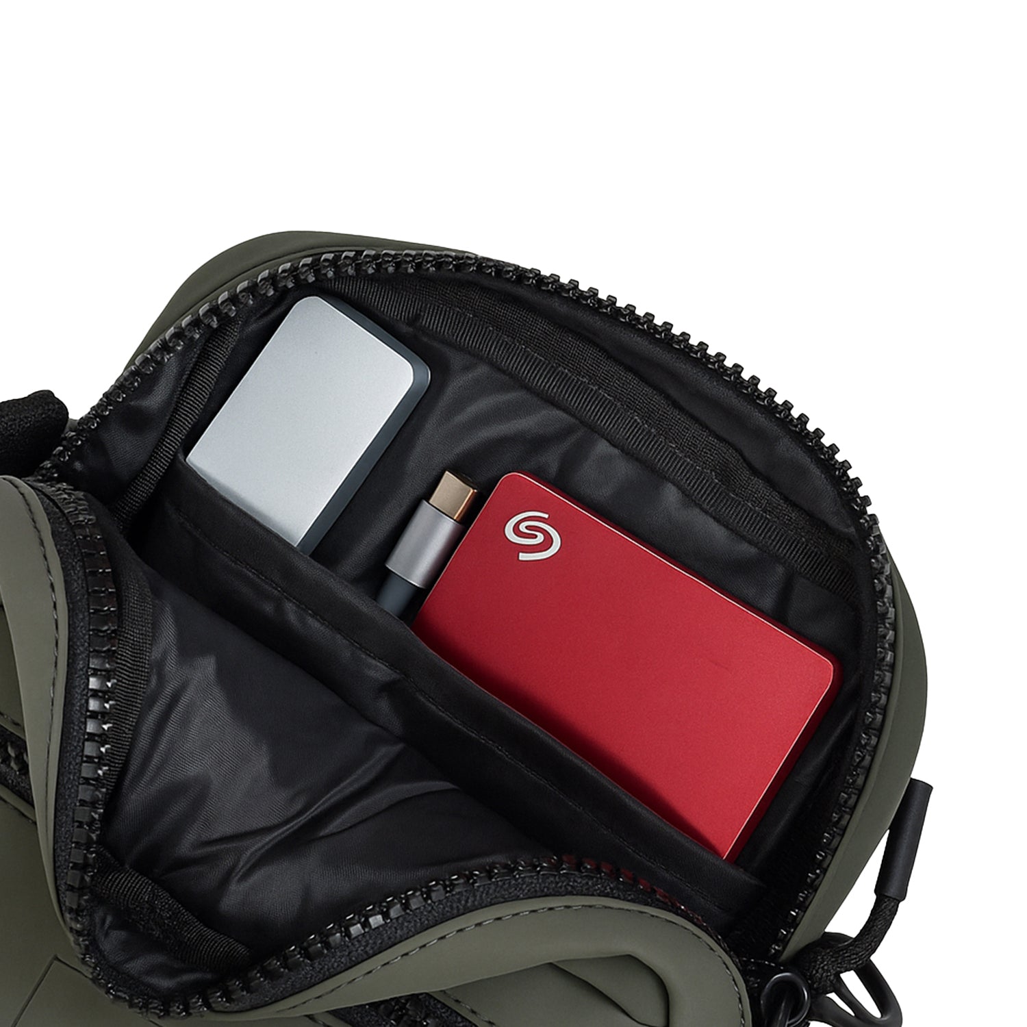 Interior of the Noma Olive bag showcasing organized storage with a silver gadget and red hard drive.