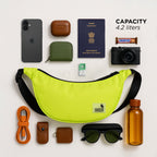 The Zuki lime green sling bag with everyday essentials like phone, passport, and camera, showcasing its 4.2-liter capacity.