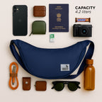 The Zuki Navy side sling bag surrounded by essential travel items, showcasing its compact design and 4.2-liter capacity.